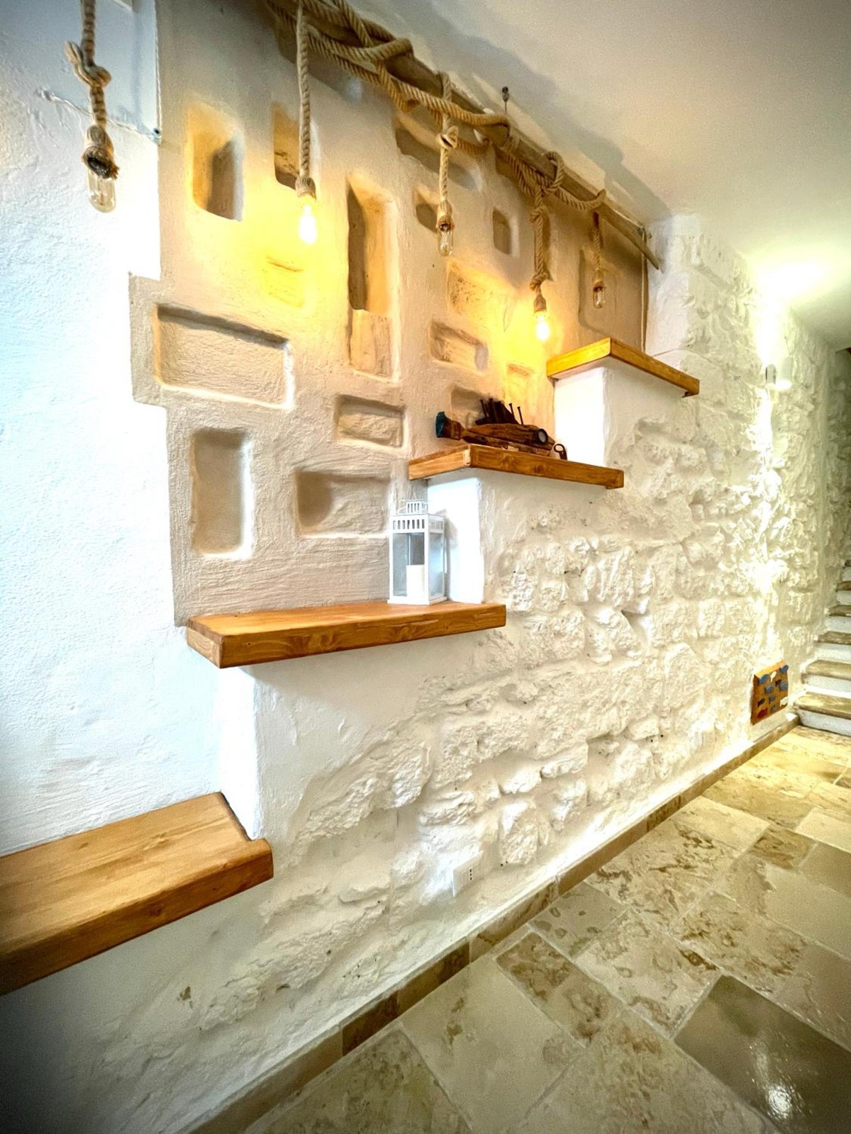 Il corridoio con le mensole di legno sul muro in pietra