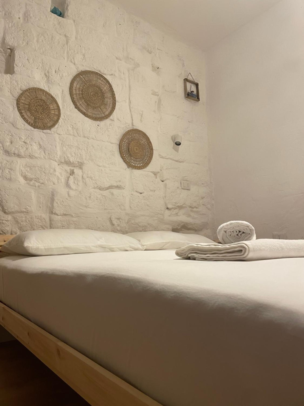 Il letto con gli asciugamani piegati e i piatti di paglia al muro