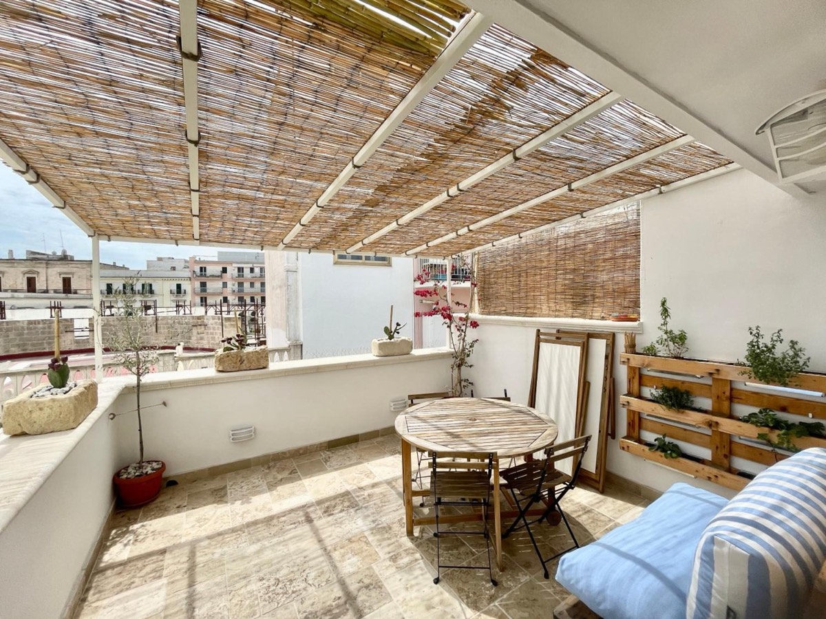 La terrazza sotto il graticcio di canne, con il tavolo e un divanetto