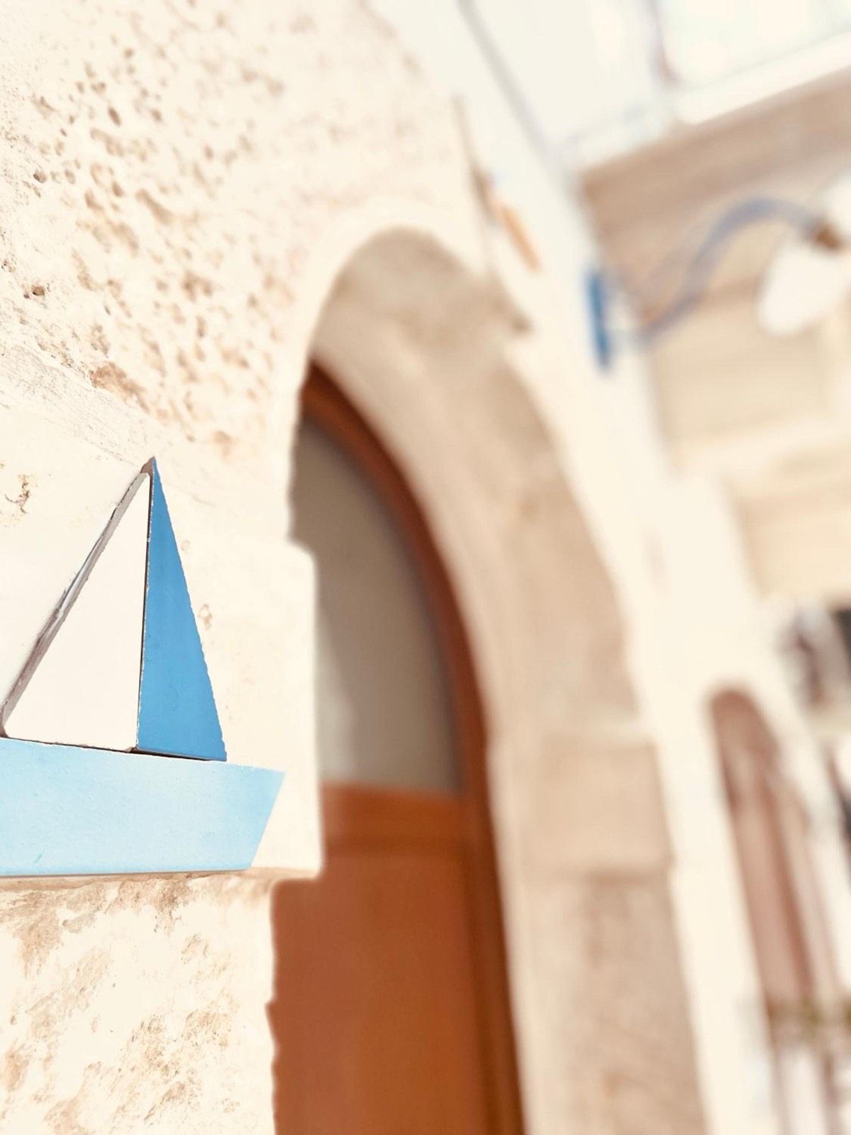 Una barchetta a vela azzurra appesa al muro, accanto alla porta ad arco