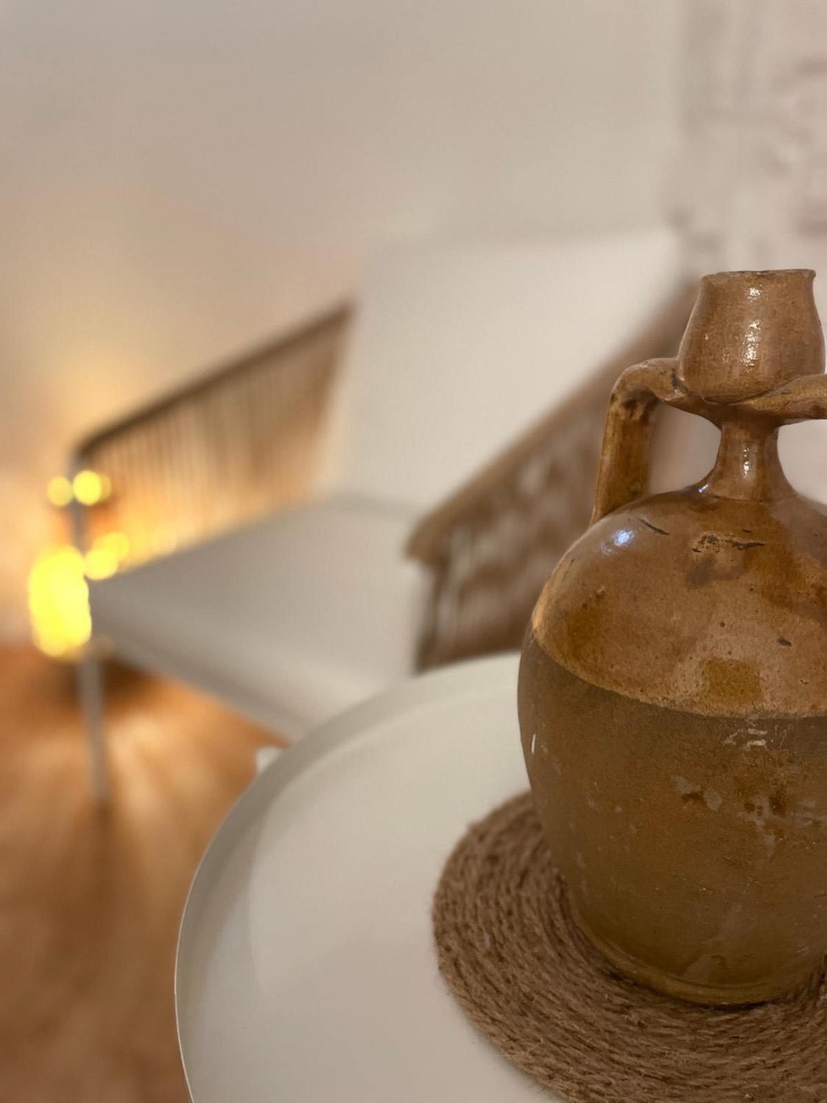 Una brocca di ceramica su un tavolino, con una luce accesa dietro