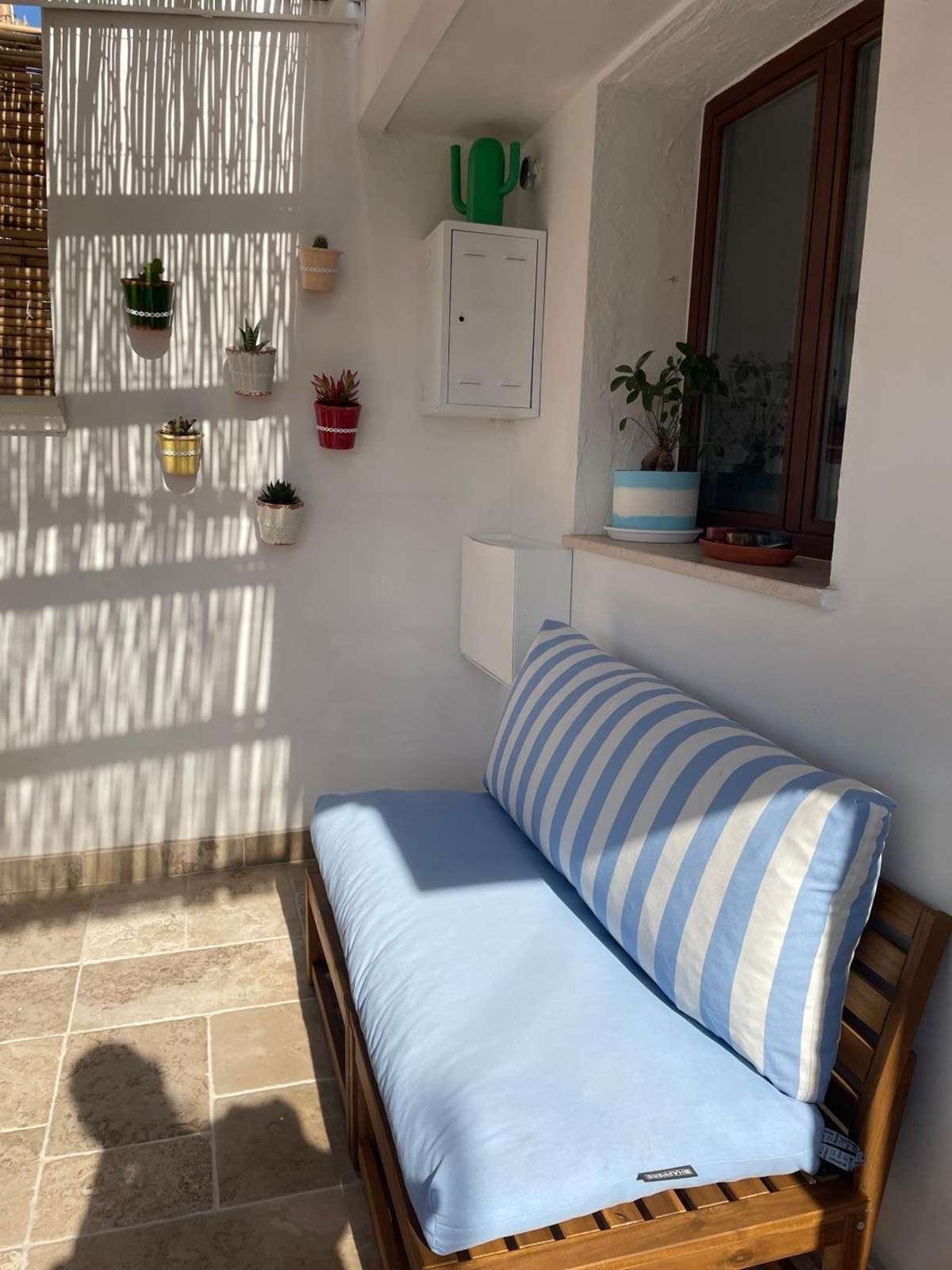 Un divanetto con i cuscini a righe azzurre, accanto alla finestra