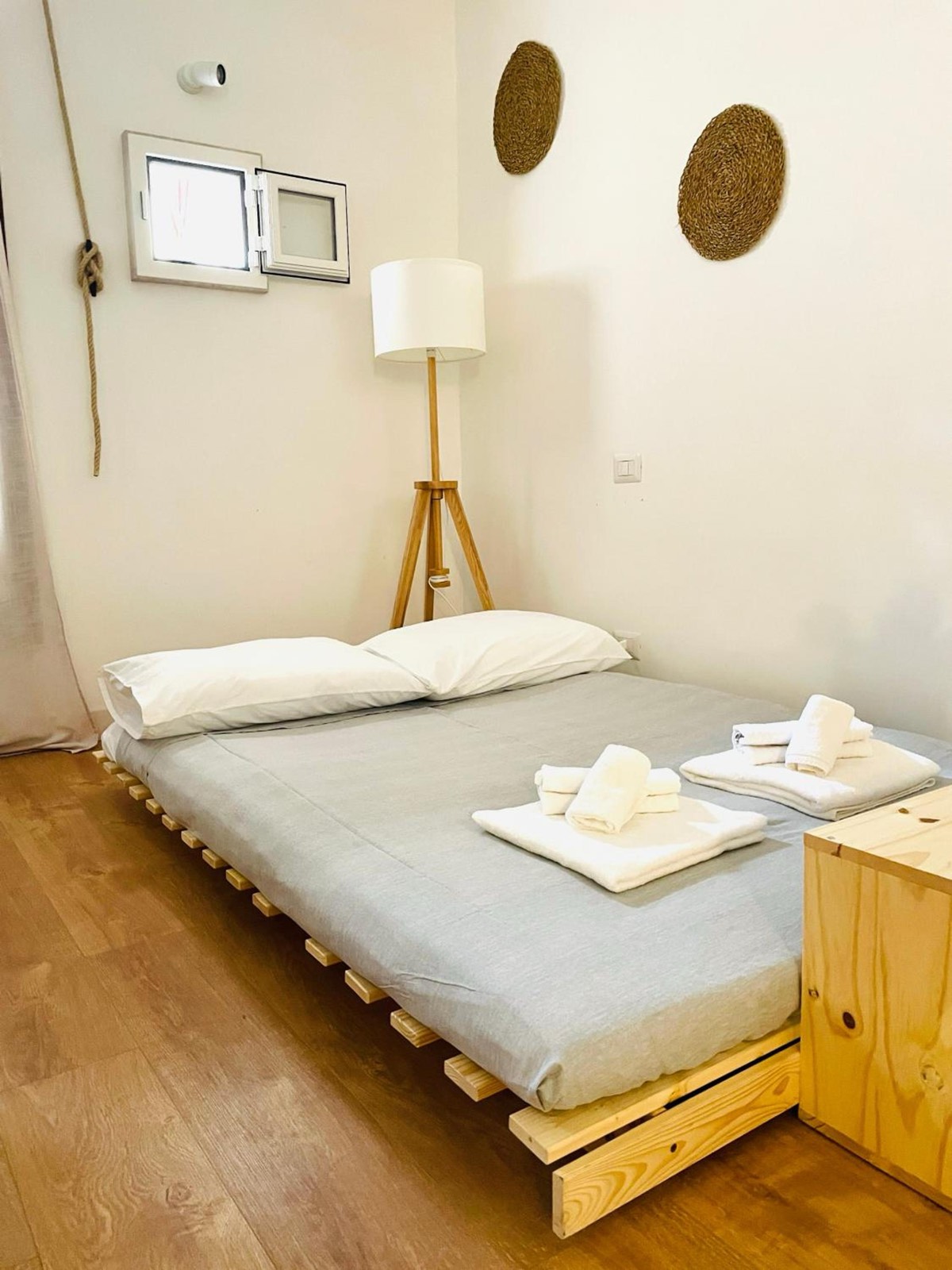 Il letto matrimoniale su una base di legno, con una lampada e le piante